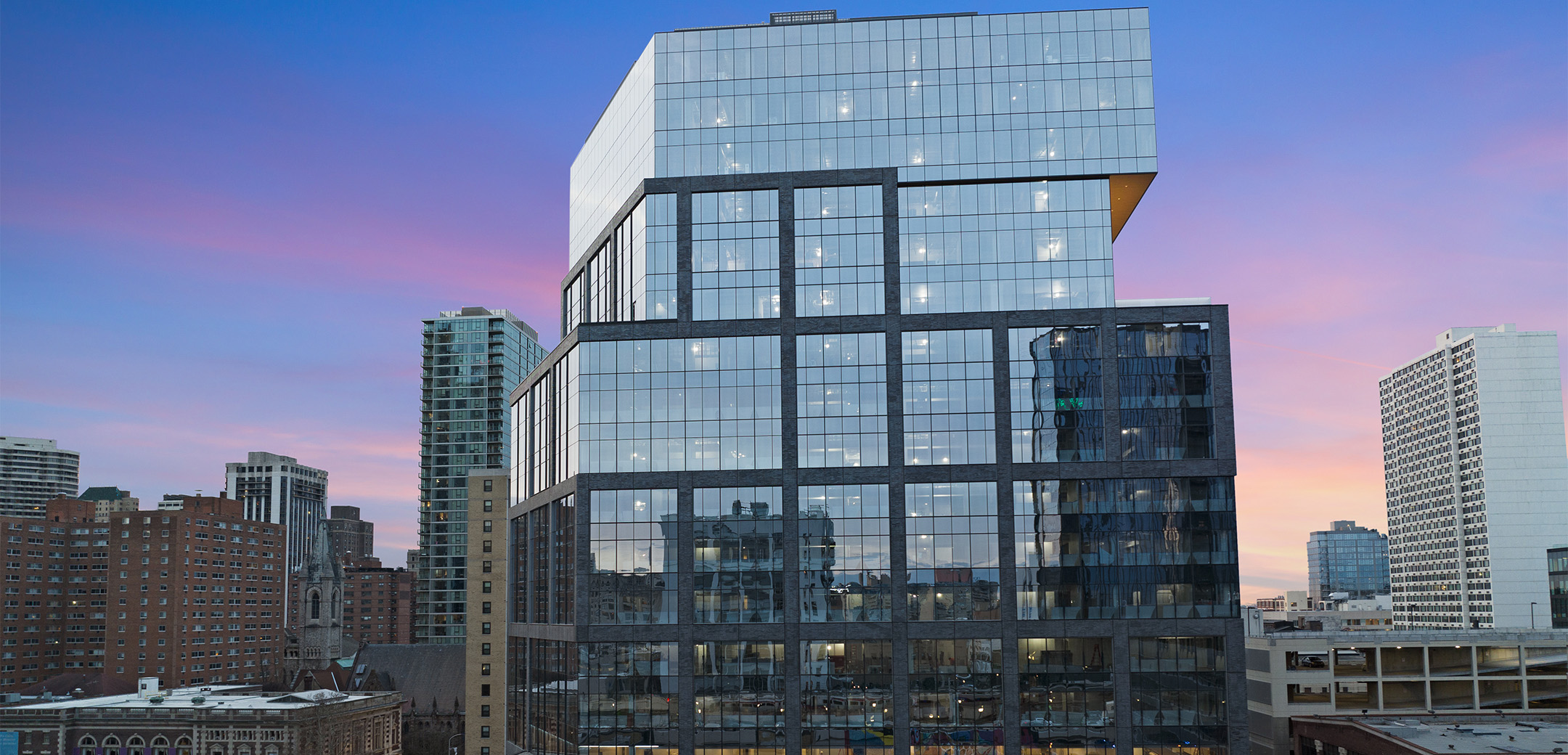 The exterior view of 2222 Market Street featuring a glass facade and the city of Philadelphia in the background