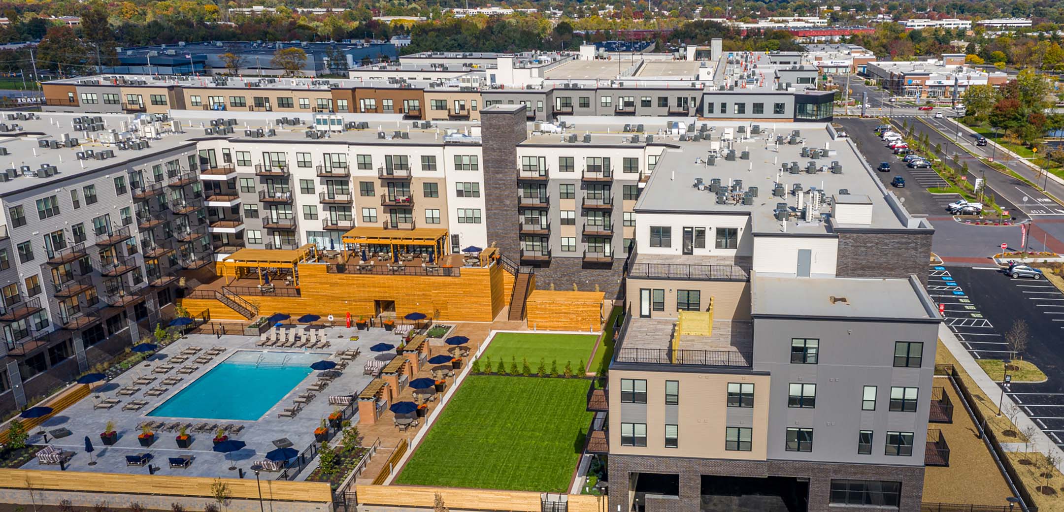 A close up view of the Promenade at Upper Dublin building, showcasing the inner courtyard with an elevated rest space, pool, grass lawn and balconies overlooking it.