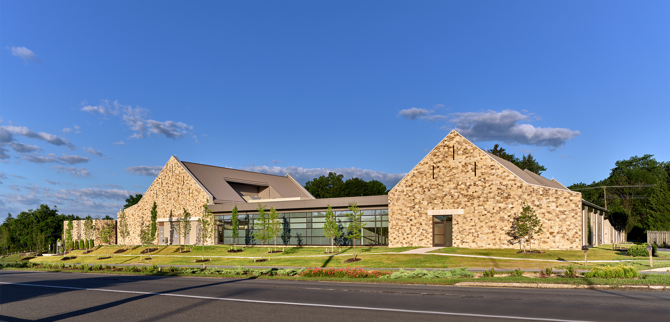 A street side view of the Astoria Health building street showcasing the stone wall and glass hallway