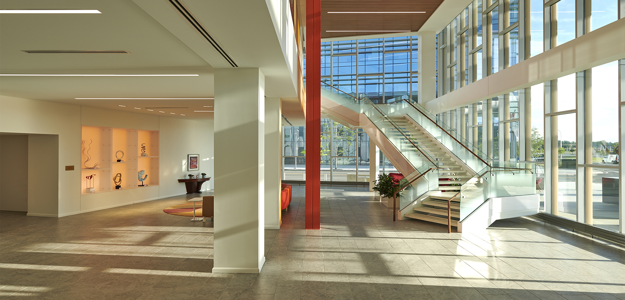 Empty lobby of Chemours Discovery Hub with a staircase, sofa, and wall filled with decorative vases.