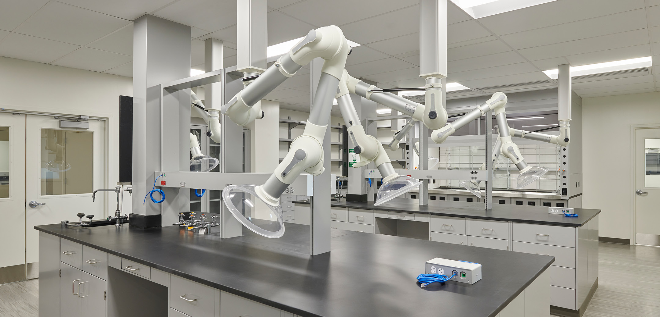 An interior view of the Chemours Discovery Hub lab, showcasing the workbenches with adjustable fume vacuums and desk top outlets.