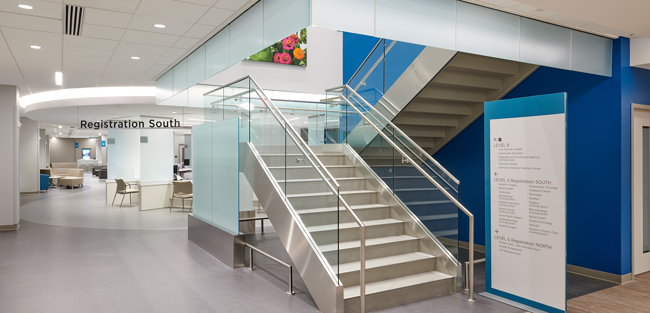 An interior view of the Main Health Women's Health Center building showcasing the registration area lobby and upwards going staircase with glass railings.