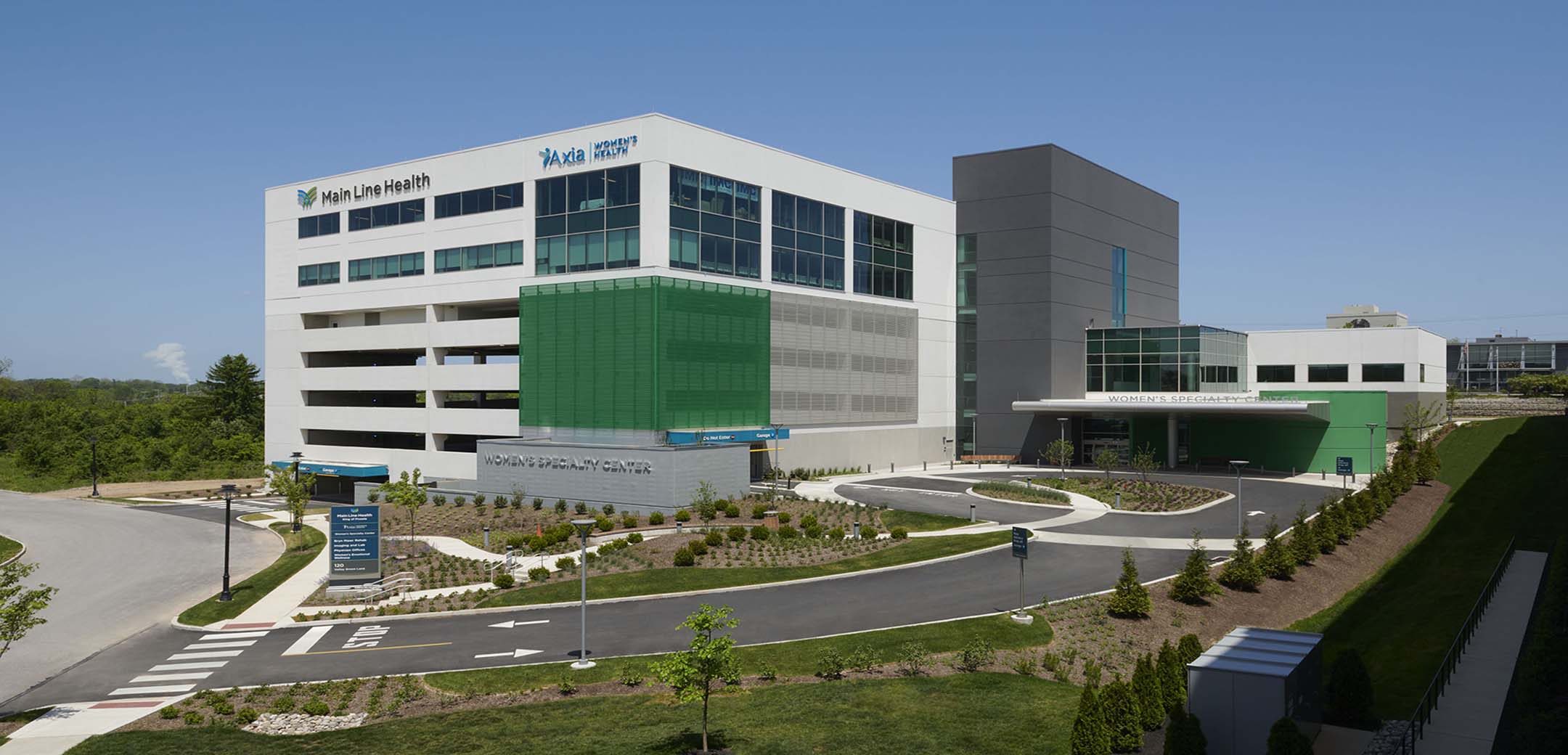 The exterior of the Main Line Health Women`s building showcasing the whole site with the driveway inside, parking building and main entrance.