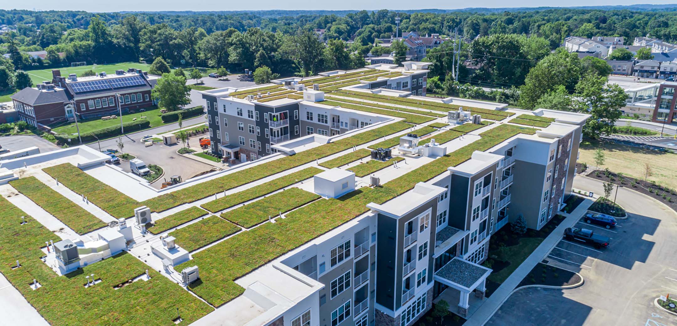 An aerial shot of the Airdrie building, showcasing the large layout, parking amendments, grass roof and the general area.