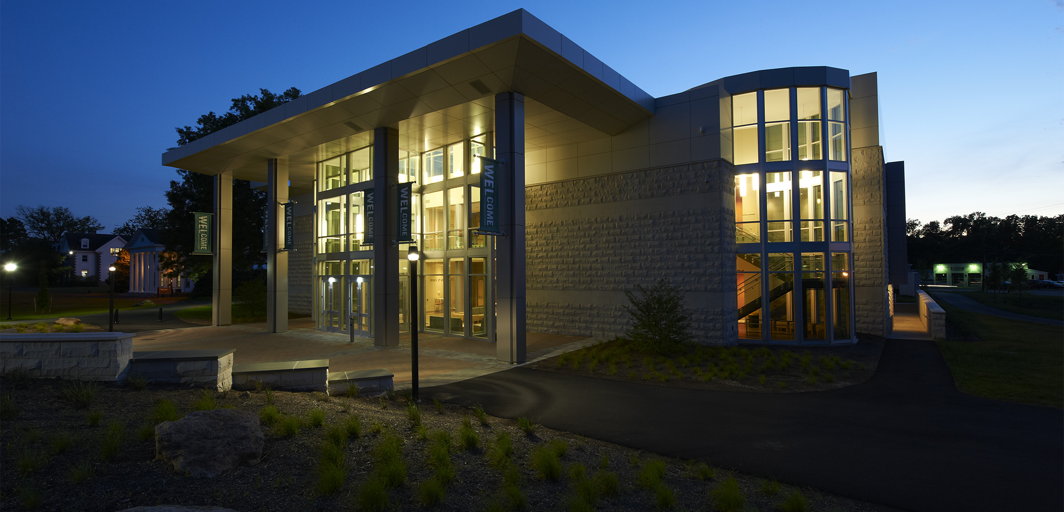 An angled night image of the Delaware Valley College building showcasing the front side of the building, entrance and driveway.