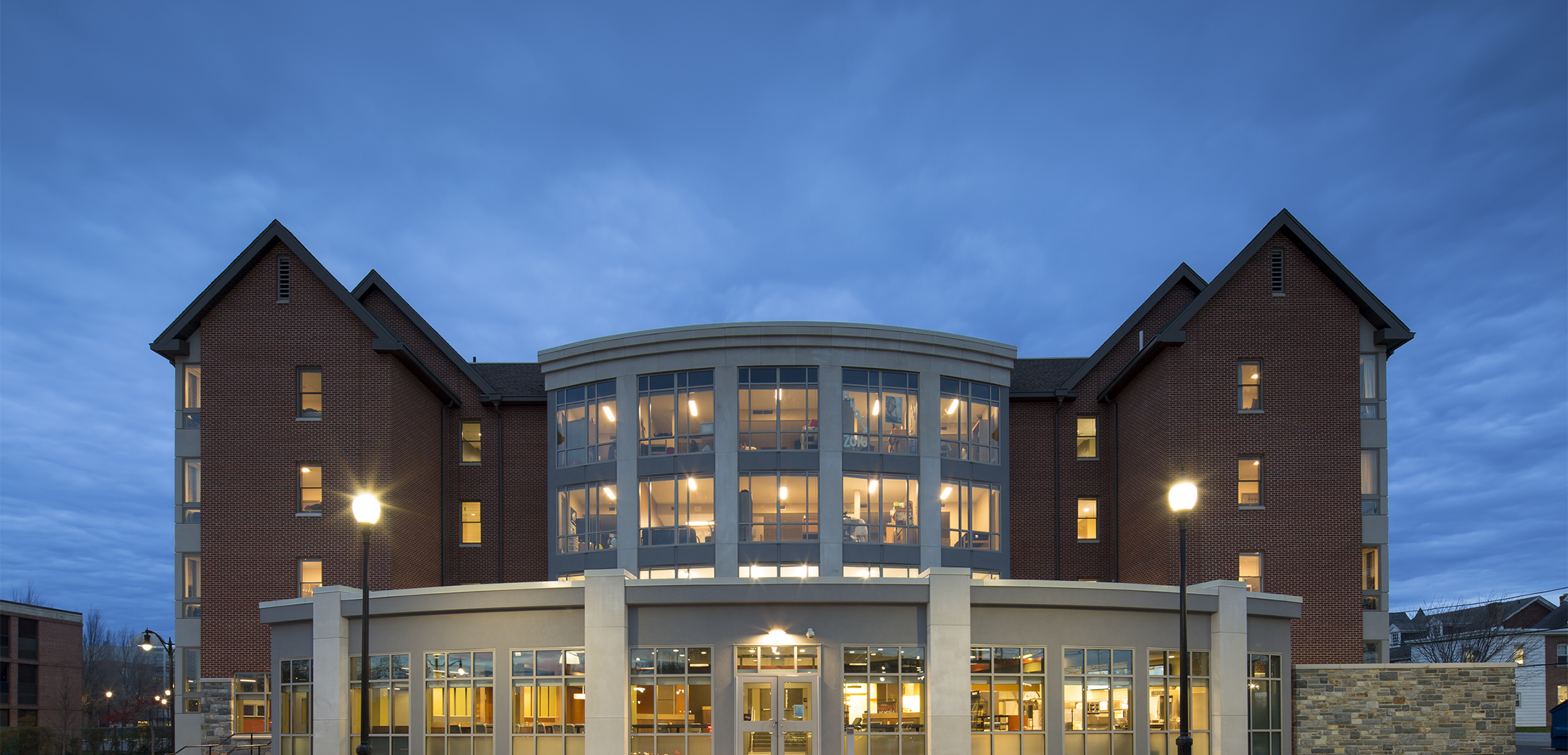 An evening view of the 4-story Widener University building back side entrance featuring a curved