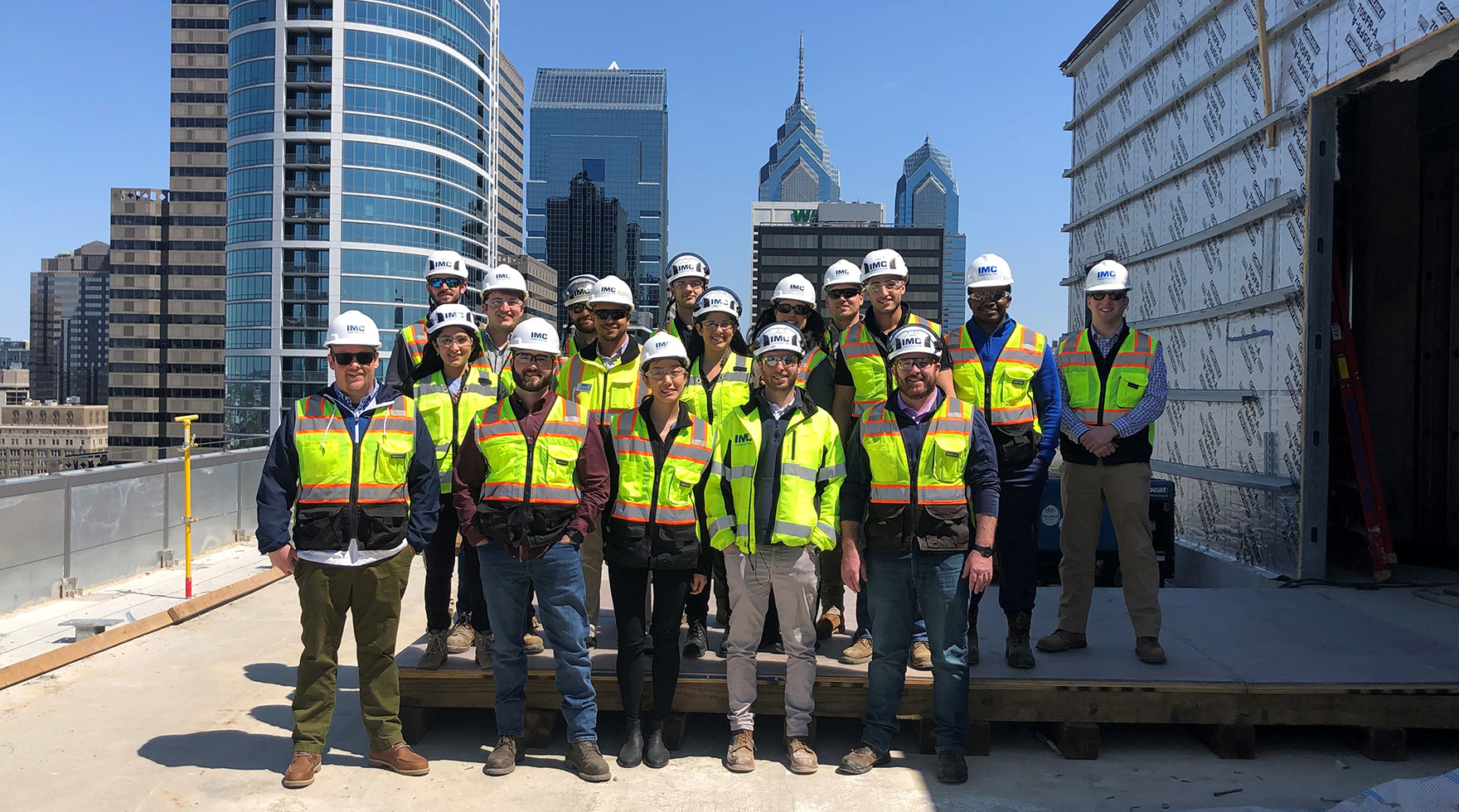 A group of IMC employees on 2222 Market Street project site wearing safety helmets and vests.