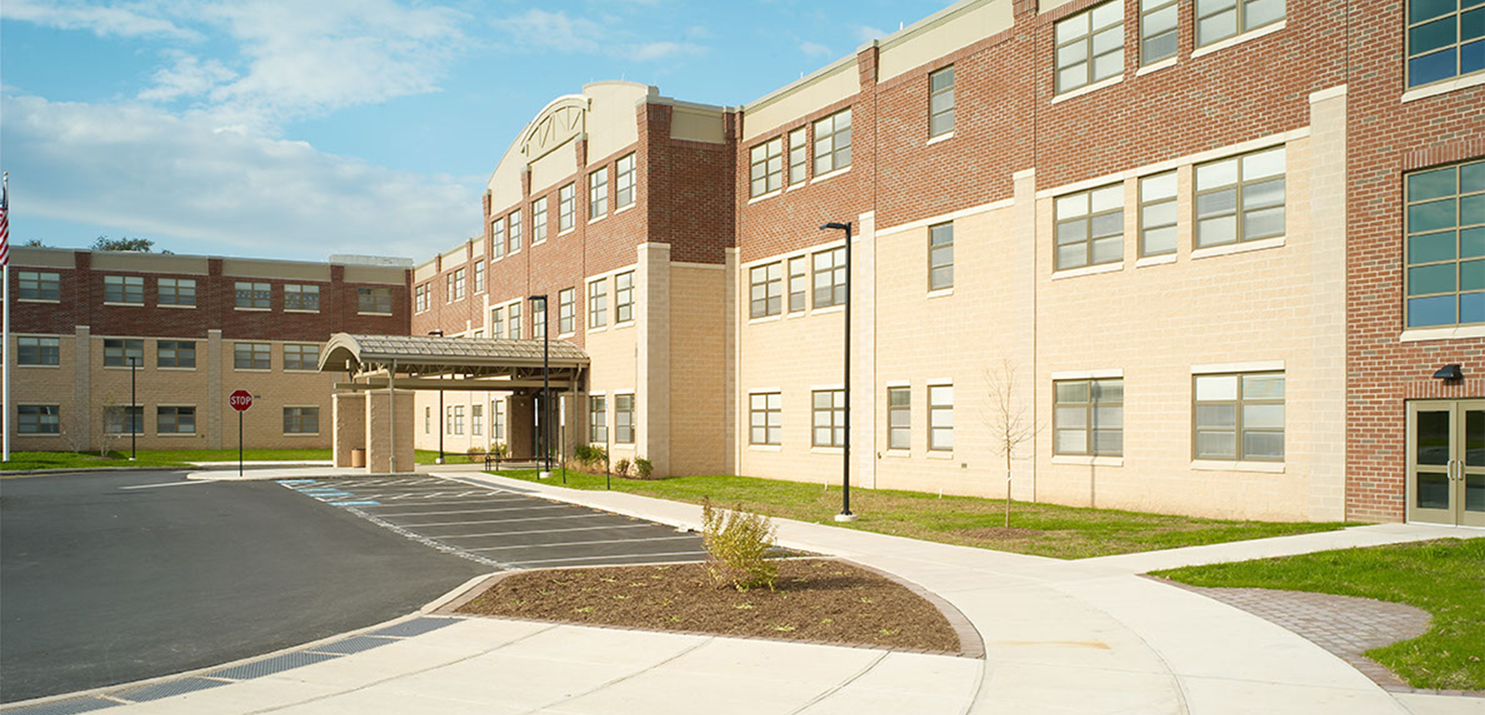 An angled view of the Phoenixville Middle School brick building showcasing the front sidewalk, side entrance and front parking lot.