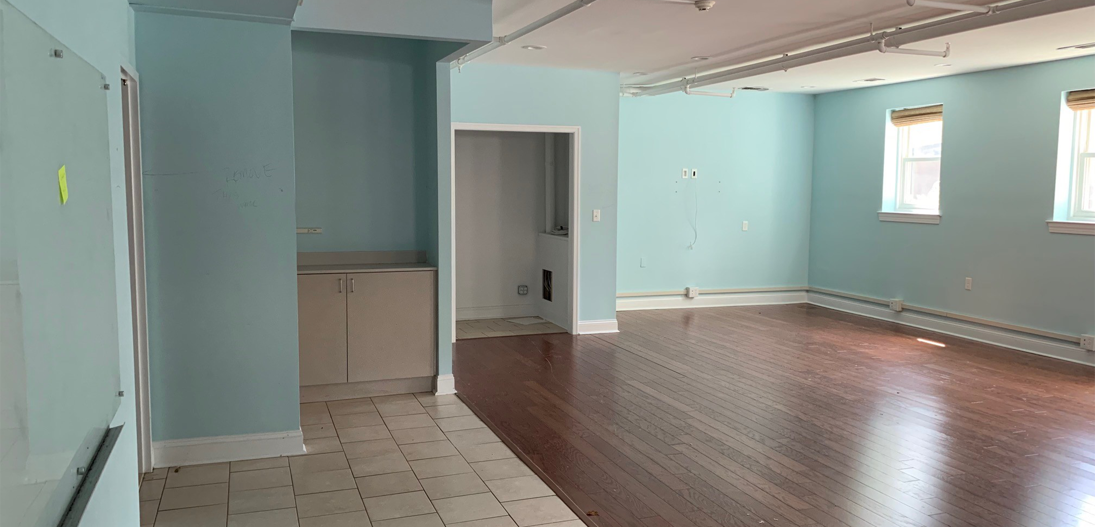 An empty room of Philadelphia Integrative Psychiatry with half white tiles and half wood floors with blue painted walls.