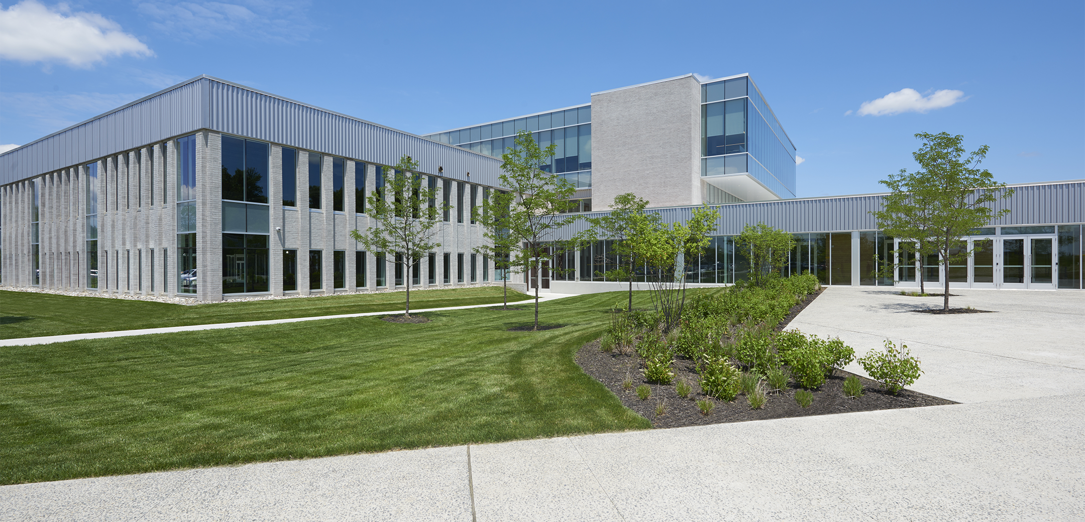 Arborcrest Corporate Campus featuring a two-story, modern, office building with full-height glass cladding and landscaping in the front.