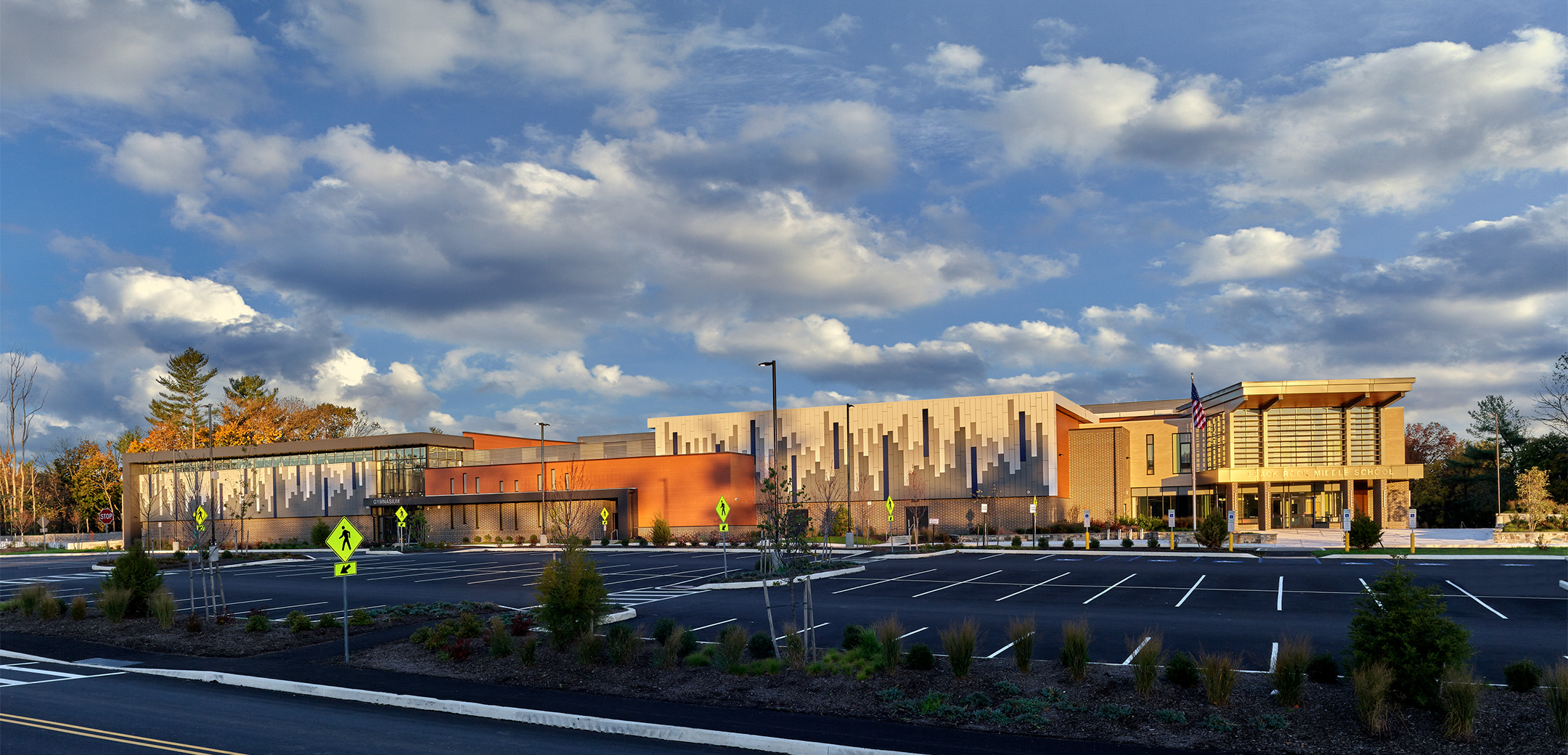 The side of Black Rock Middle School featuring a large brick building and wood facade