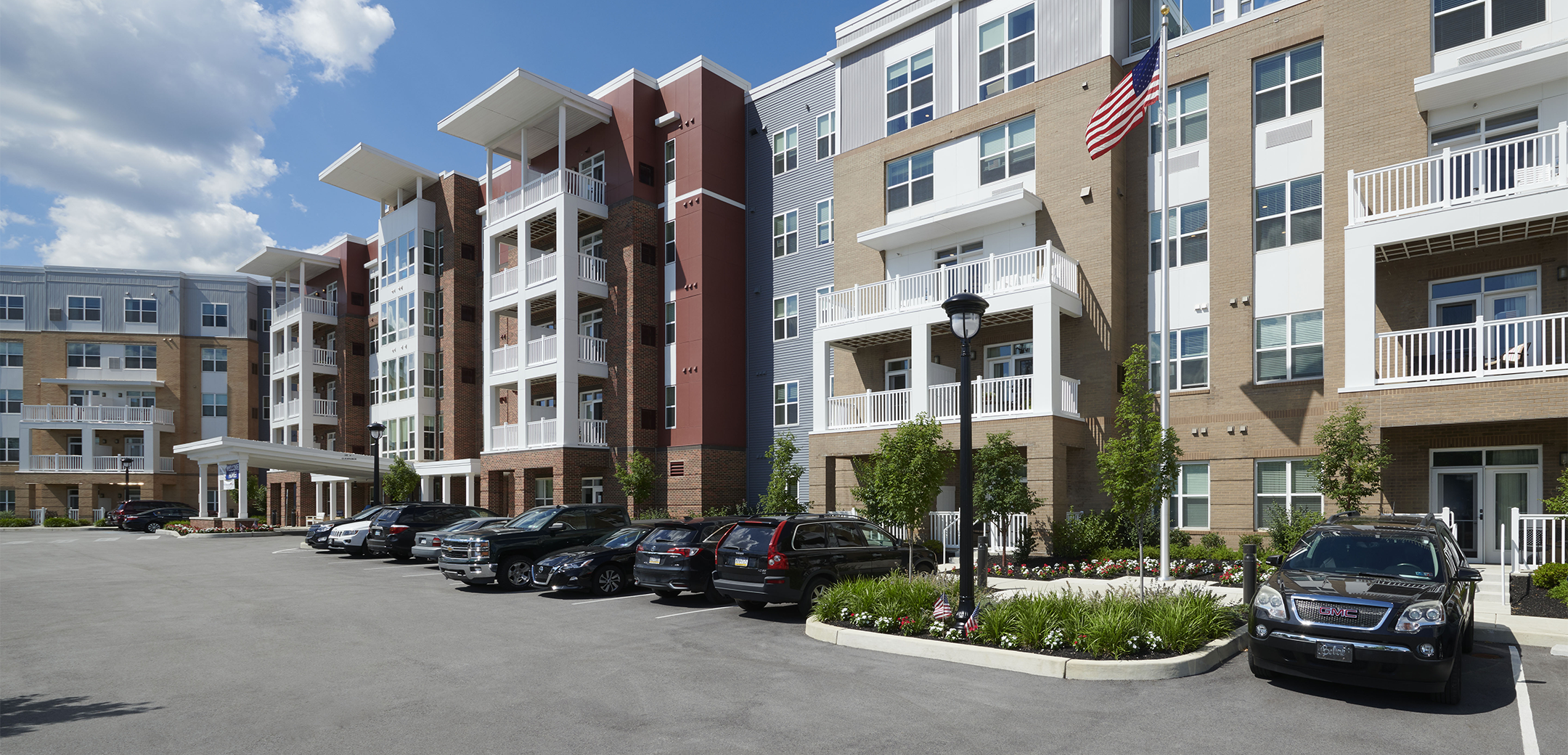 An exterior view of the Brightview Devon mixed brick and panel building showcasing the white accented windows and balconies with a front parking lot.