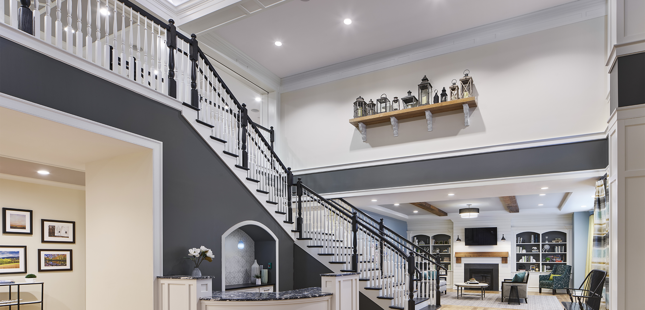 An interior view of the Arbor Terrace Exton staircase leading up to the second floor with white accent panels and grey walls with an open concept living room in the background.