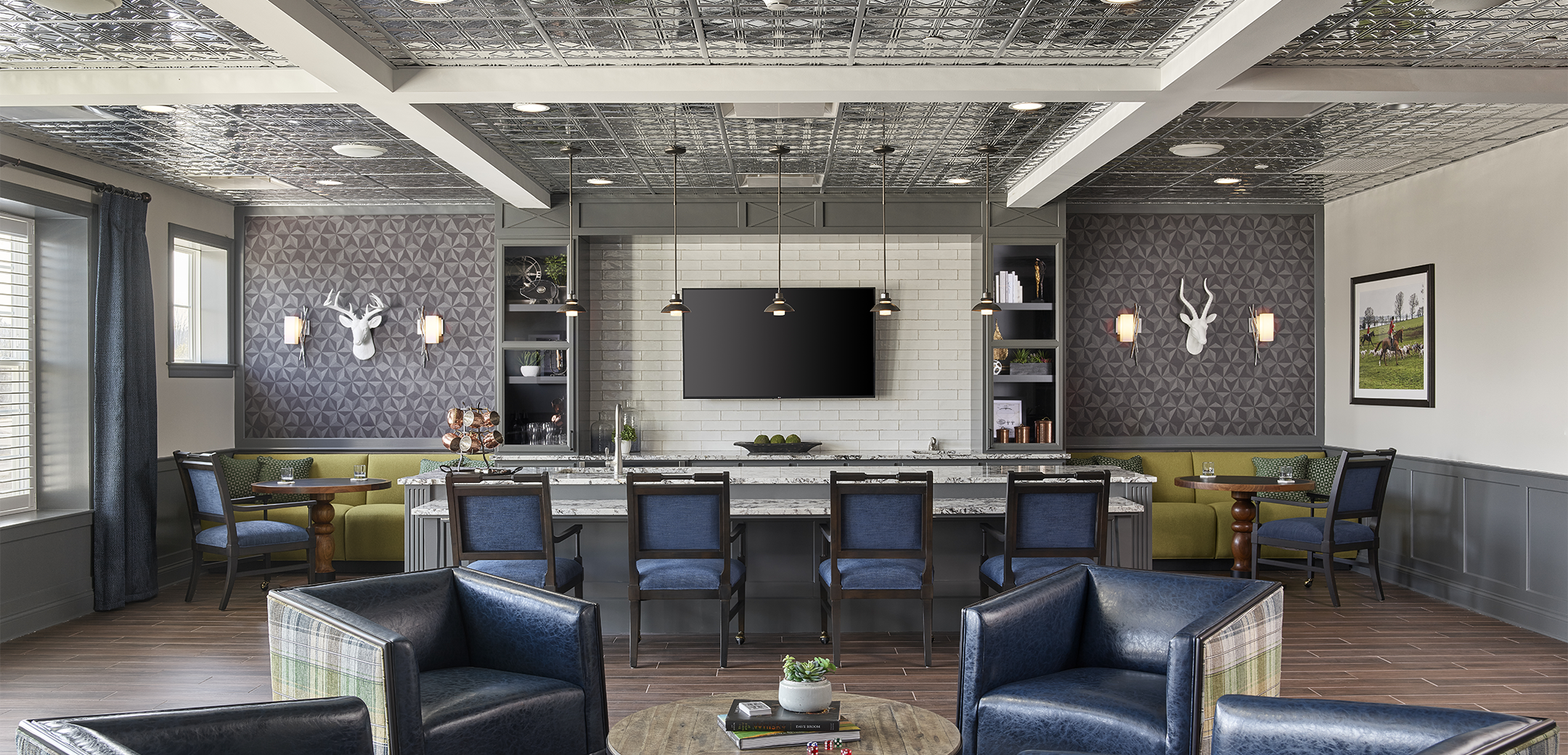 An interior view of the Arbor Terrace Exton rest space with reflective metallic ceiling, blue leather chairs and a bar in the background.