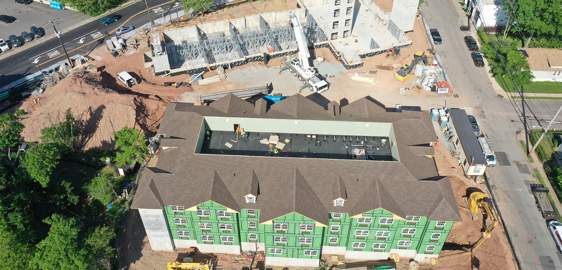 The aerial view of Chelsea Senior Living showing two buildings under construction, the front building with green exterior walls and the back building with white cement, no walls.