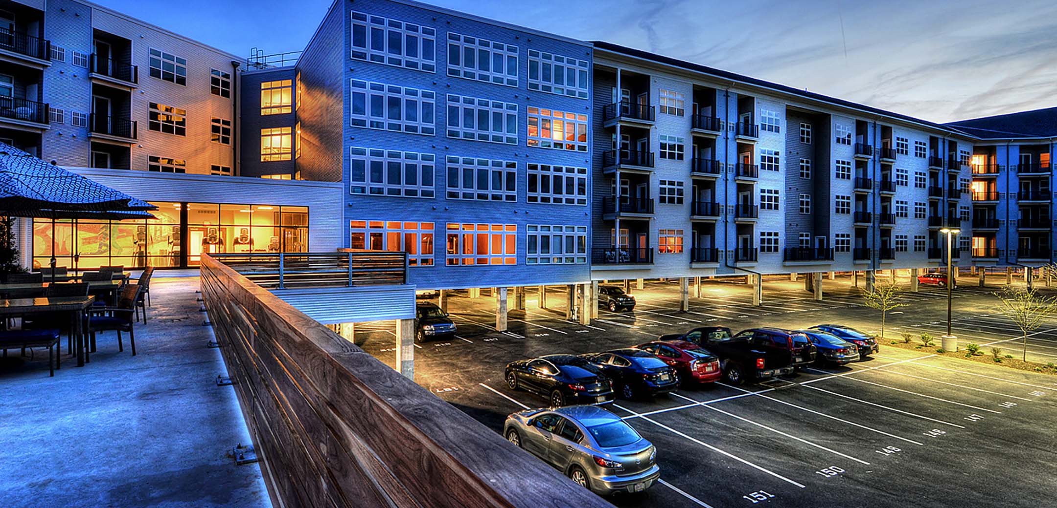 An angled view of the Phoenix Village building from the second floor balcony courtyard showcasing the floor level private parking lot.