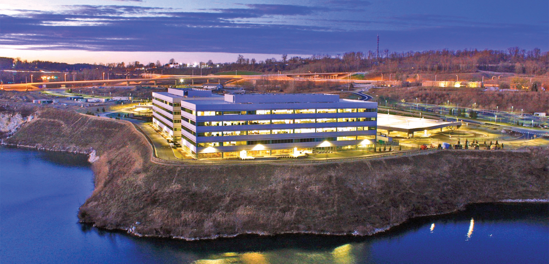 A drone shot of the Endo pharmaceutical building lit during the evening, showcasing the lakefront location.