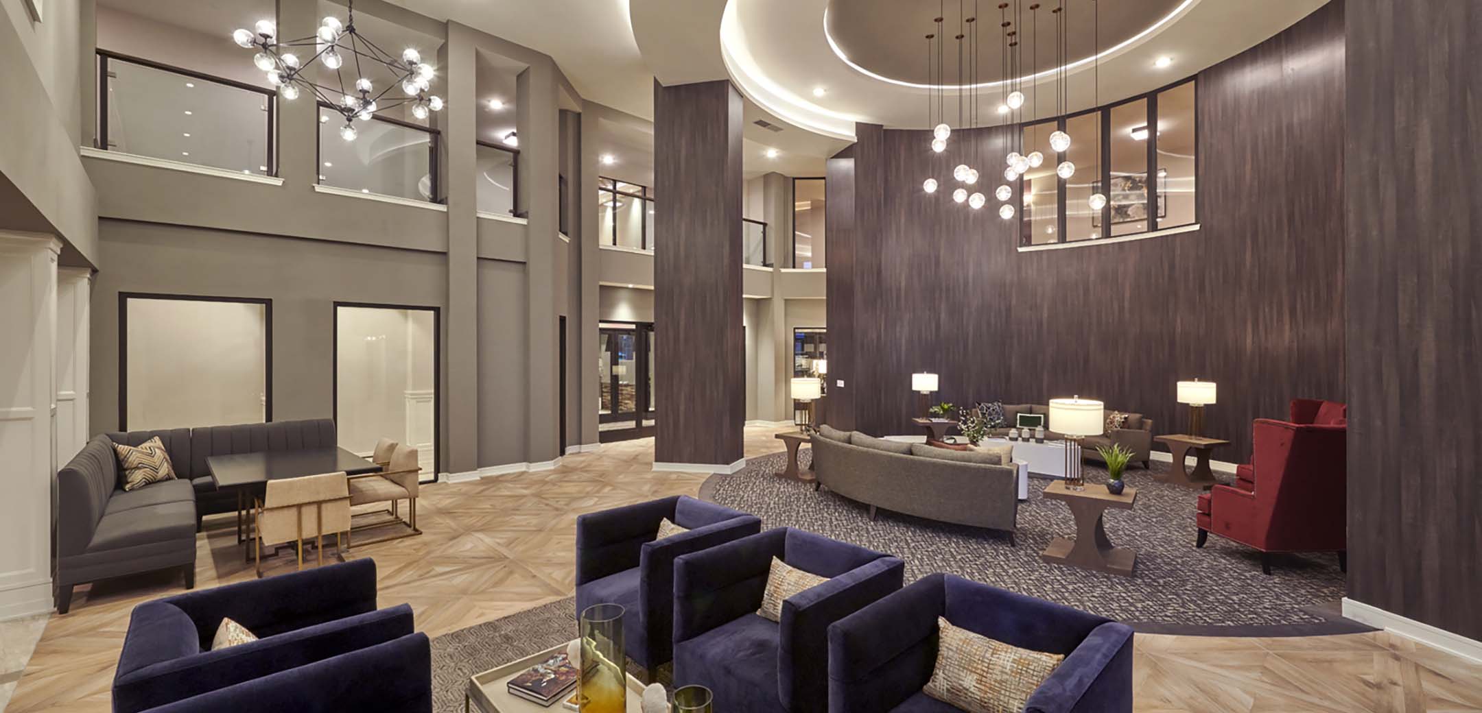 An interior view of the Granite Run Apartments building lobby sitting area, showcasing the semi-circular wood accent wall in the center and seating area in the middle.