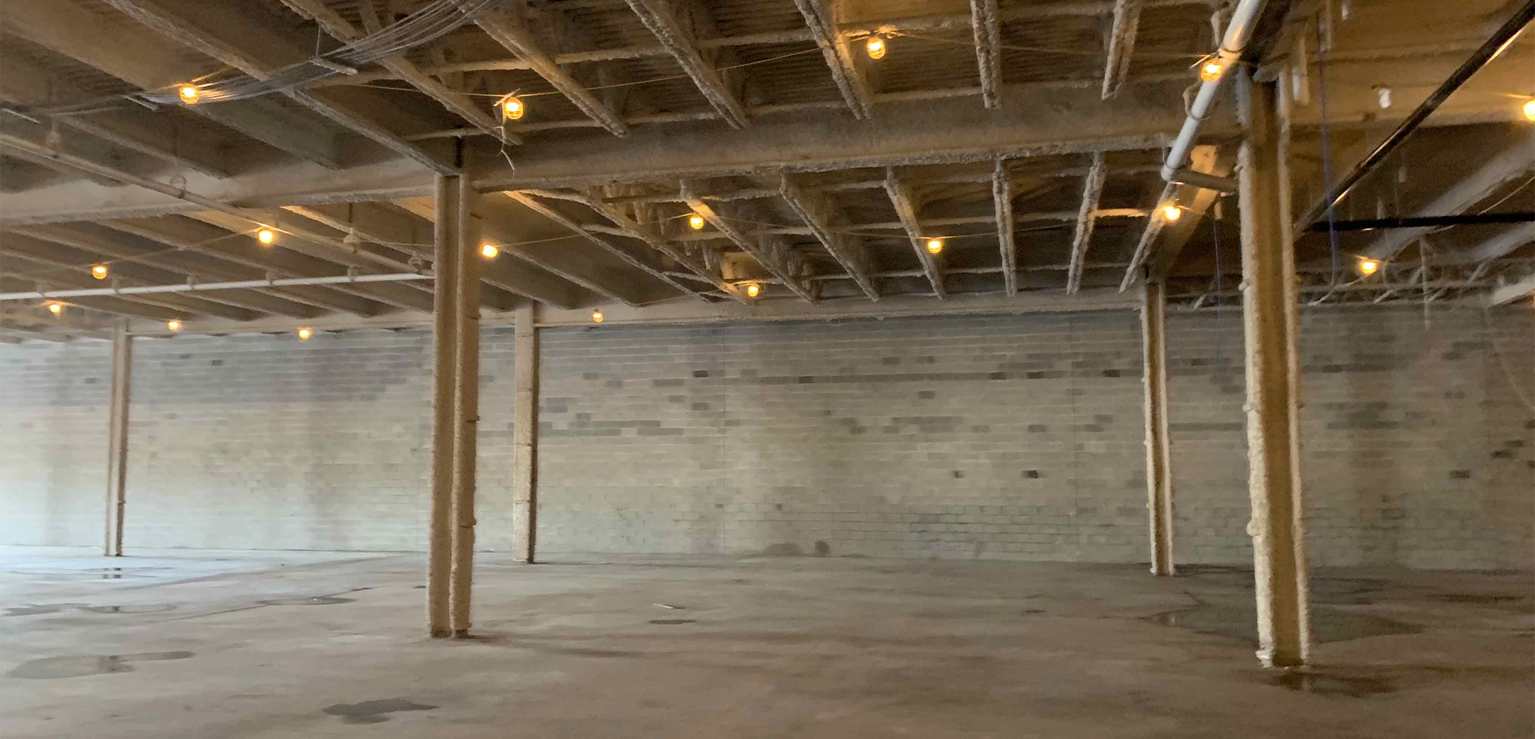 An angled interior view of the Homegoods building during the construction process, showcasing the metal steel structure and back brick wall.