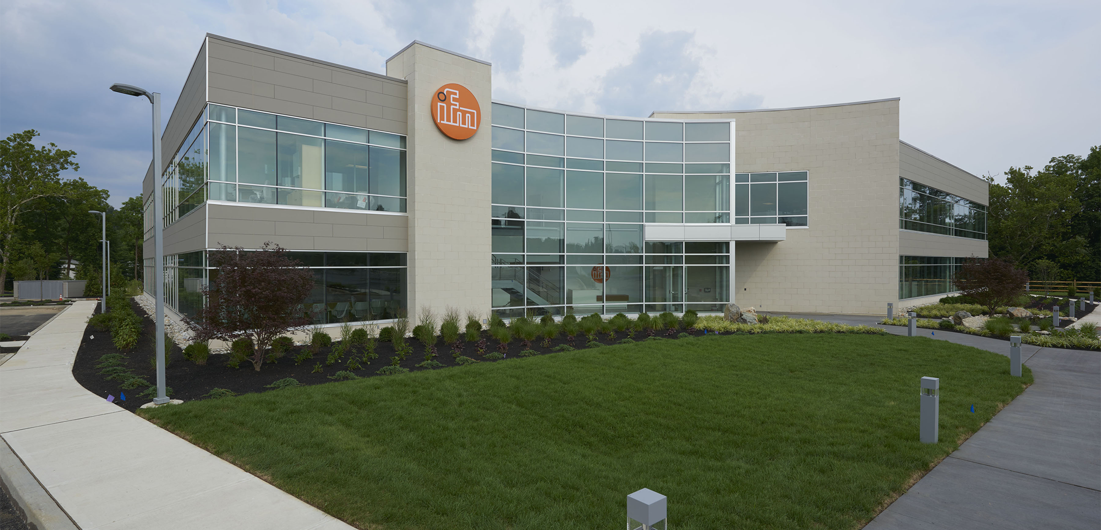 An angled view of the IFM Erector building, featuring a mix of brick and glass walls with a view on the font grass lawn.