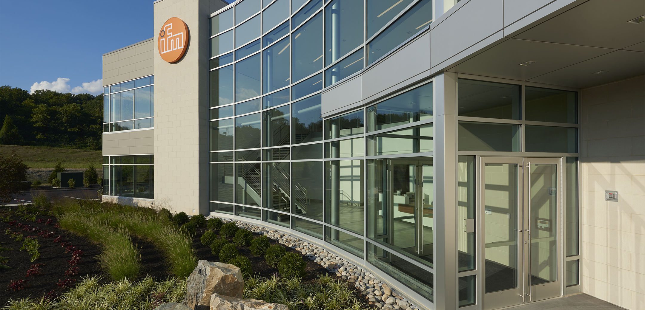 A close up view of the IMF Erector all glass entrance featuring the inside lobby and staircase.