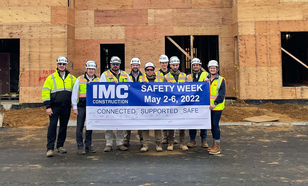 IMC Employees with hardhats and safety vests posing with Safety Week sign