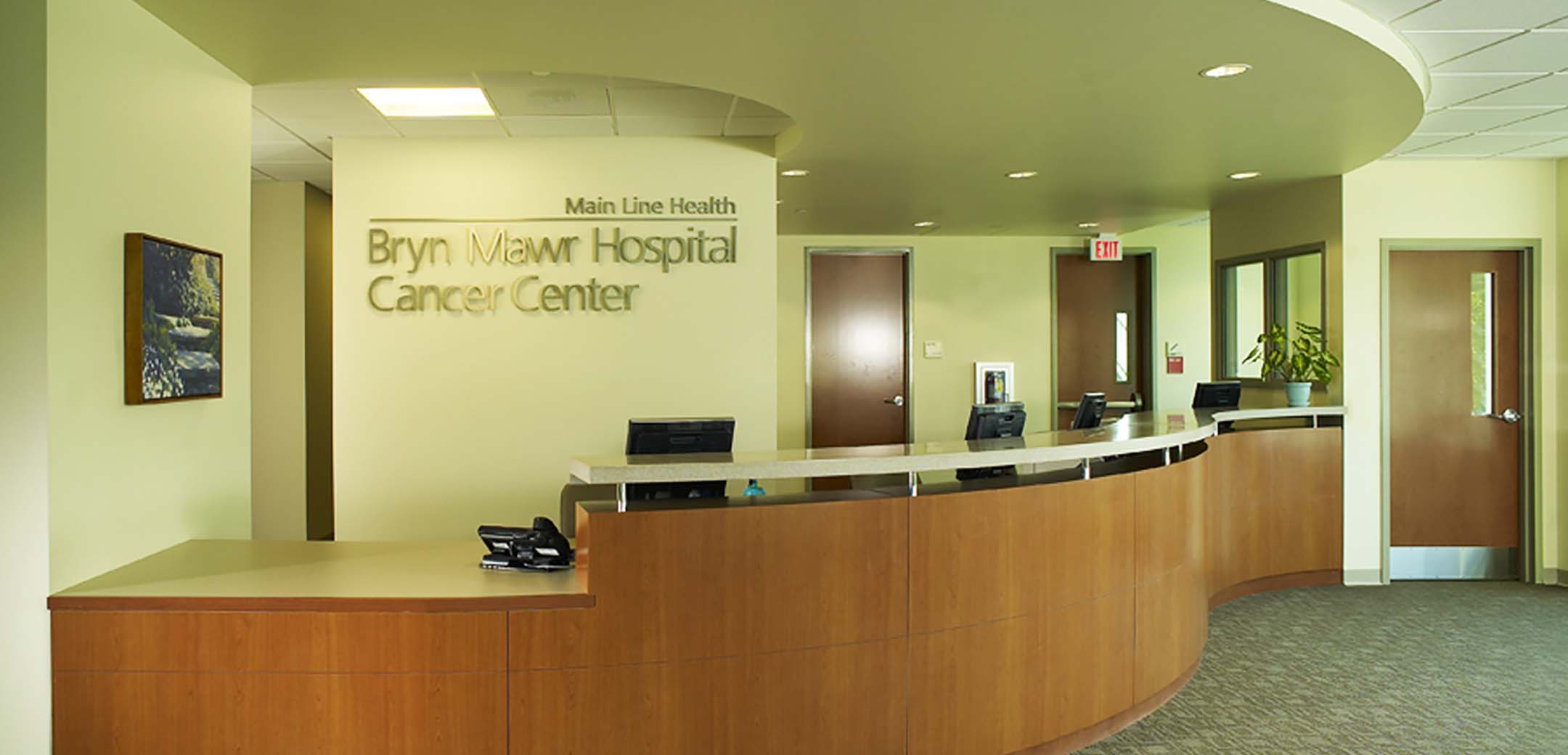 A close up image of the interior lobby of Main Line Health hospital, showcasing the reception desk and logo behind it.