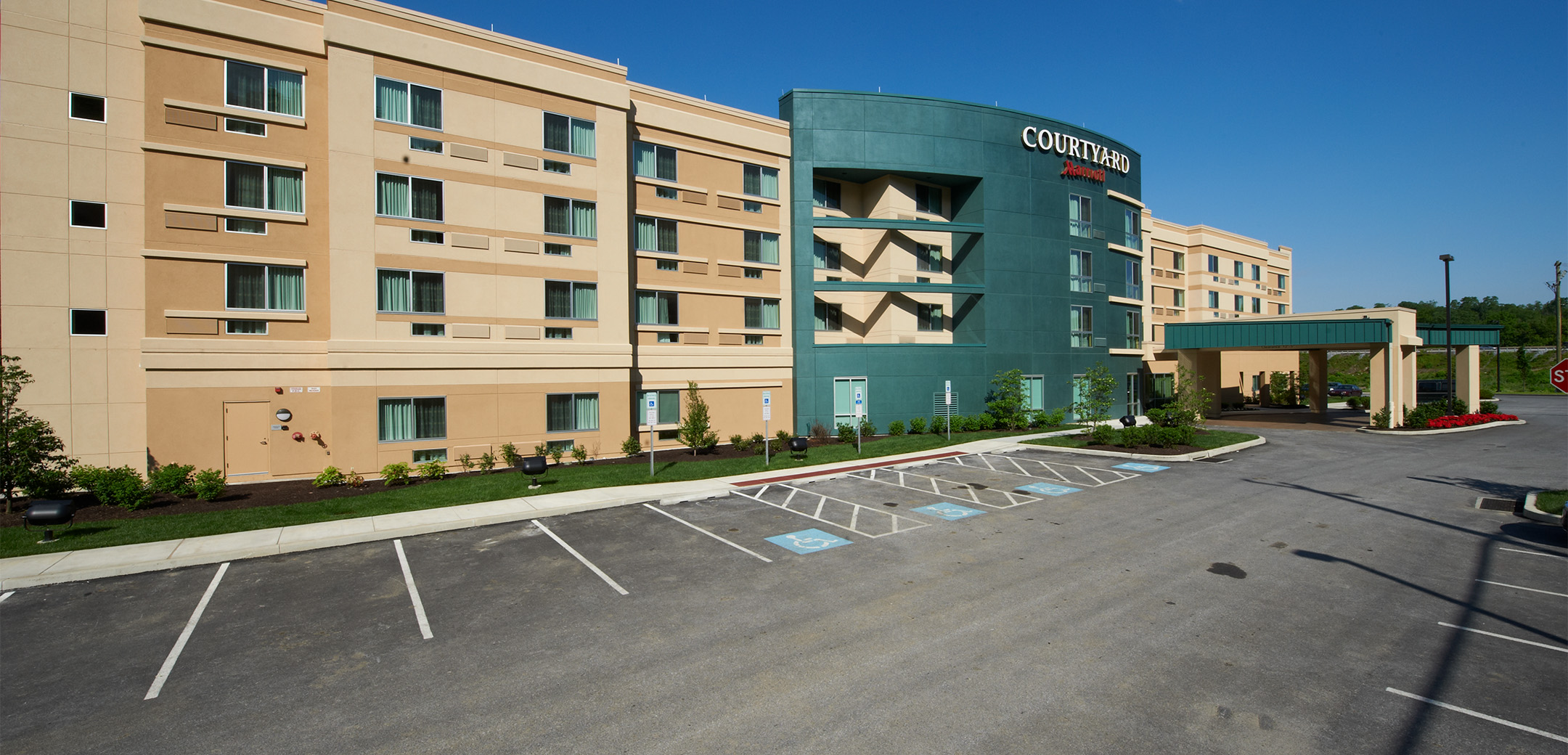 A angled view of the Marriot Courtyard hotel front enterance,showcasing the teal accents and front parking lot space.