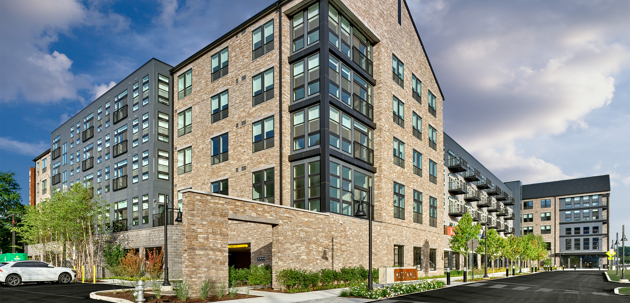 An angled view of Matson Mill Apartment building featuring the tan brick exterior with the corner of the building wrapped in glass windows.