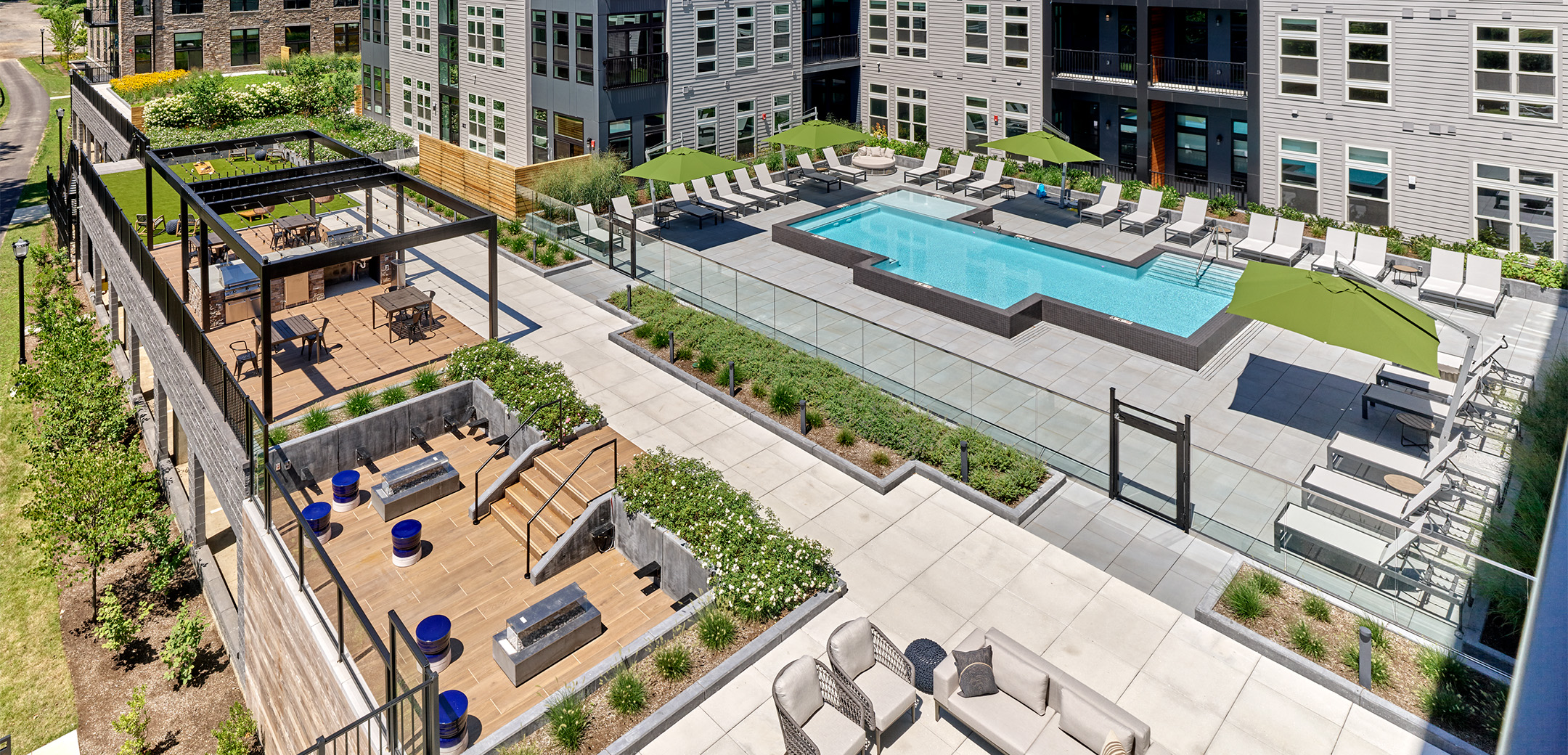 An aerial view of Matson Mill Apartment's outdoor terrace featuring a resort-style pool, sunken lounge, outdoor seating, and sun deck.