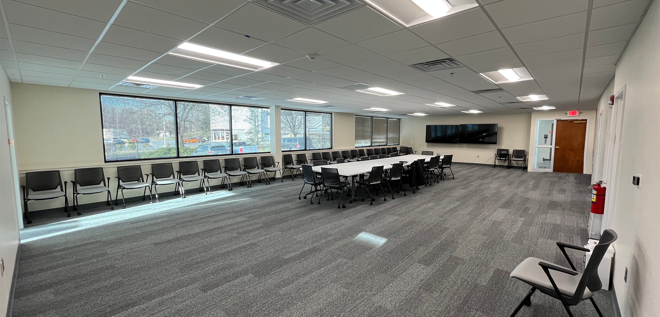 An interior view of the PA Leadership Charter School meeting room with carpet flooring and panel ceiling with a meeting table and chairs in the center.