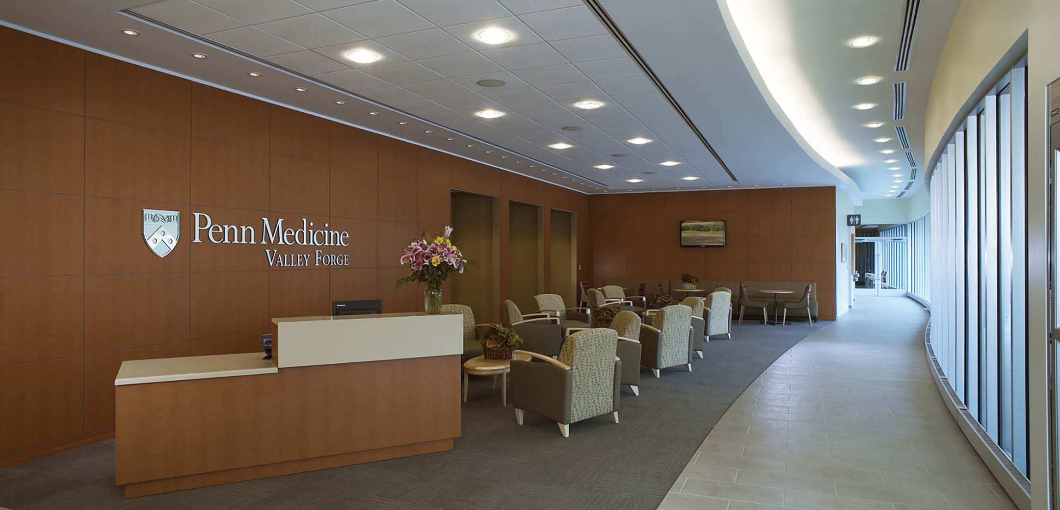 An interior view of the Pen Med VF lobby showcasing the reception desk, sitting area and glass wall corridor.