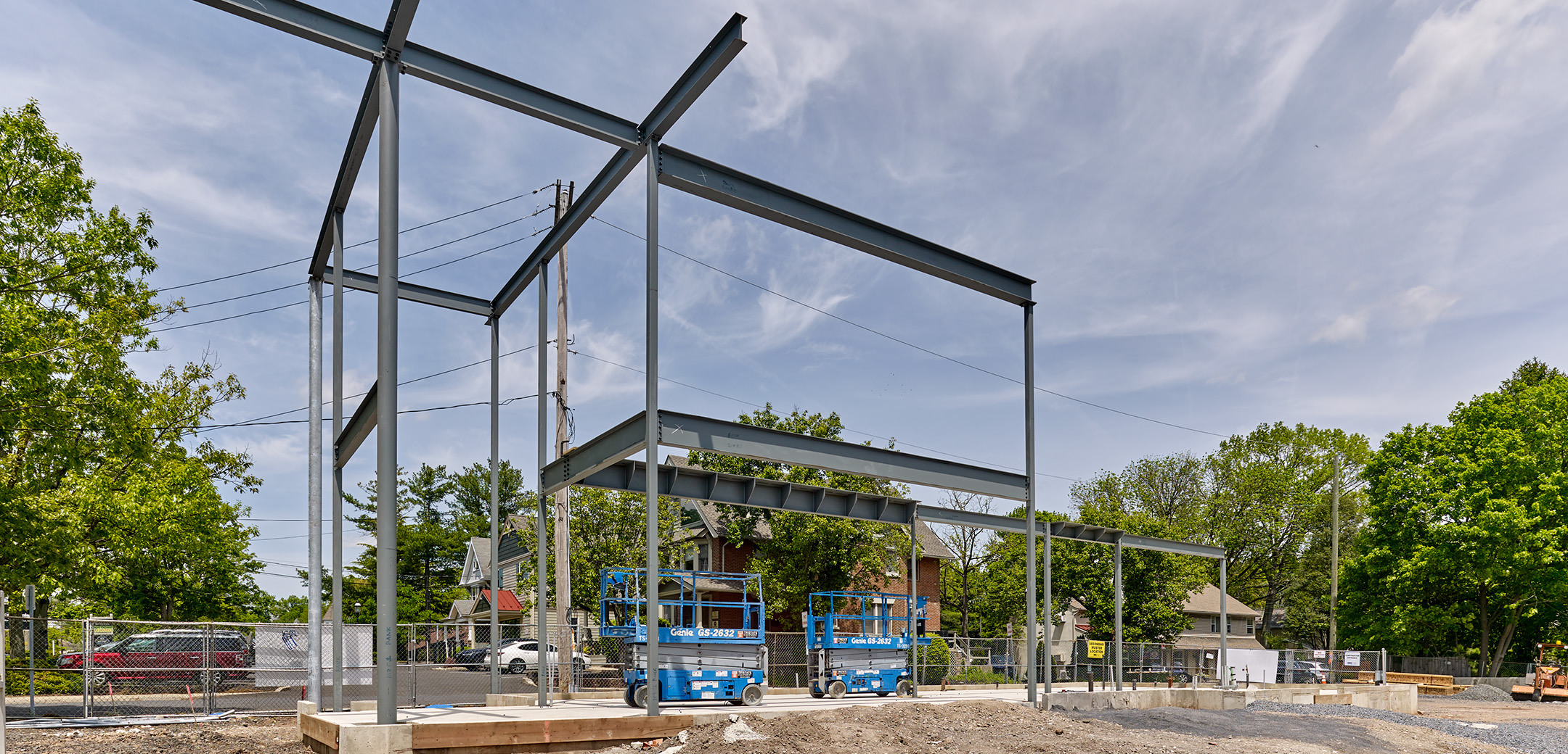 A steel frame of People's Security Bank and Trust with blue construction equipment.