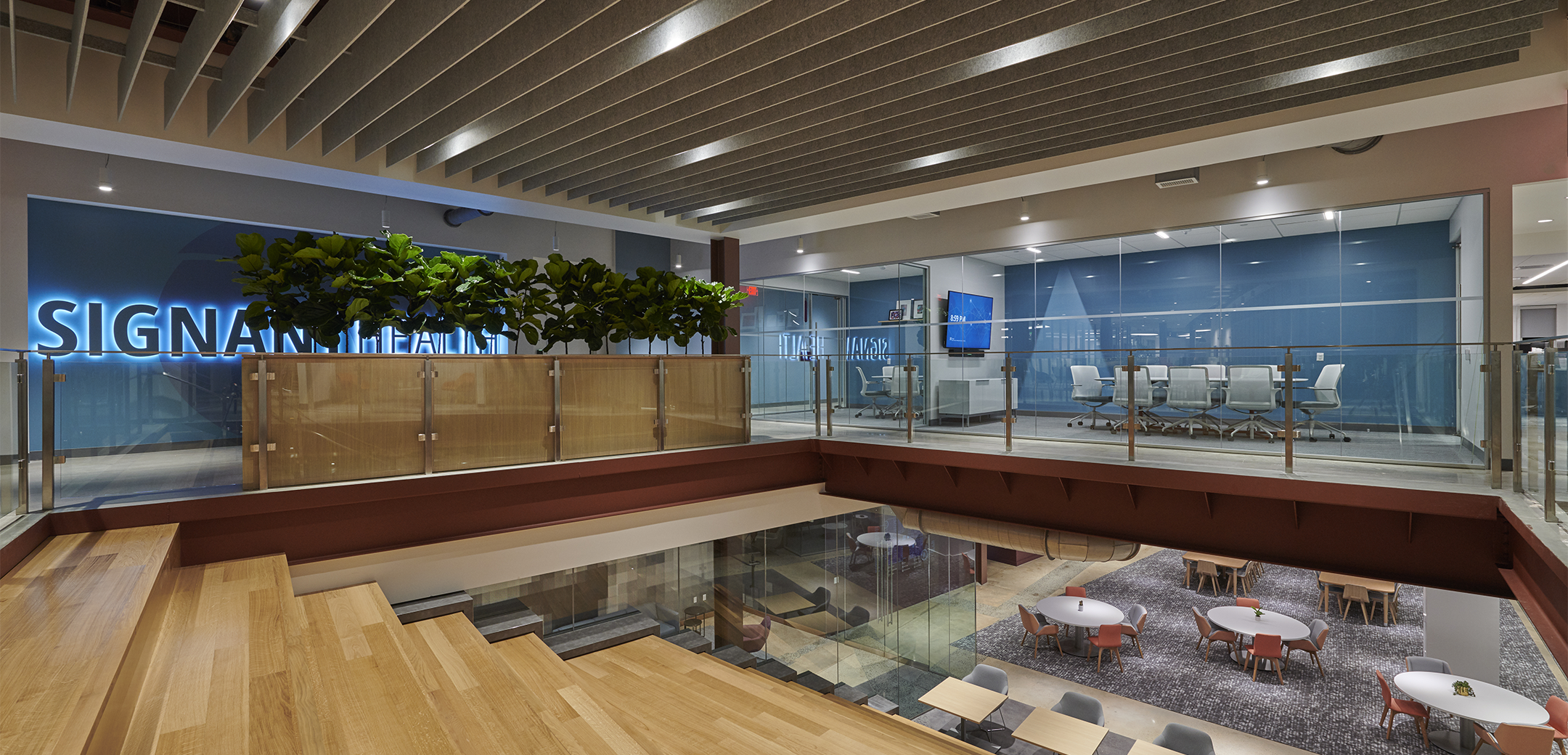 The interior space of Signant Health Headquarters featuring a wide communication staircase connecting the second floor of conference rooms and first floor of open space and tables.