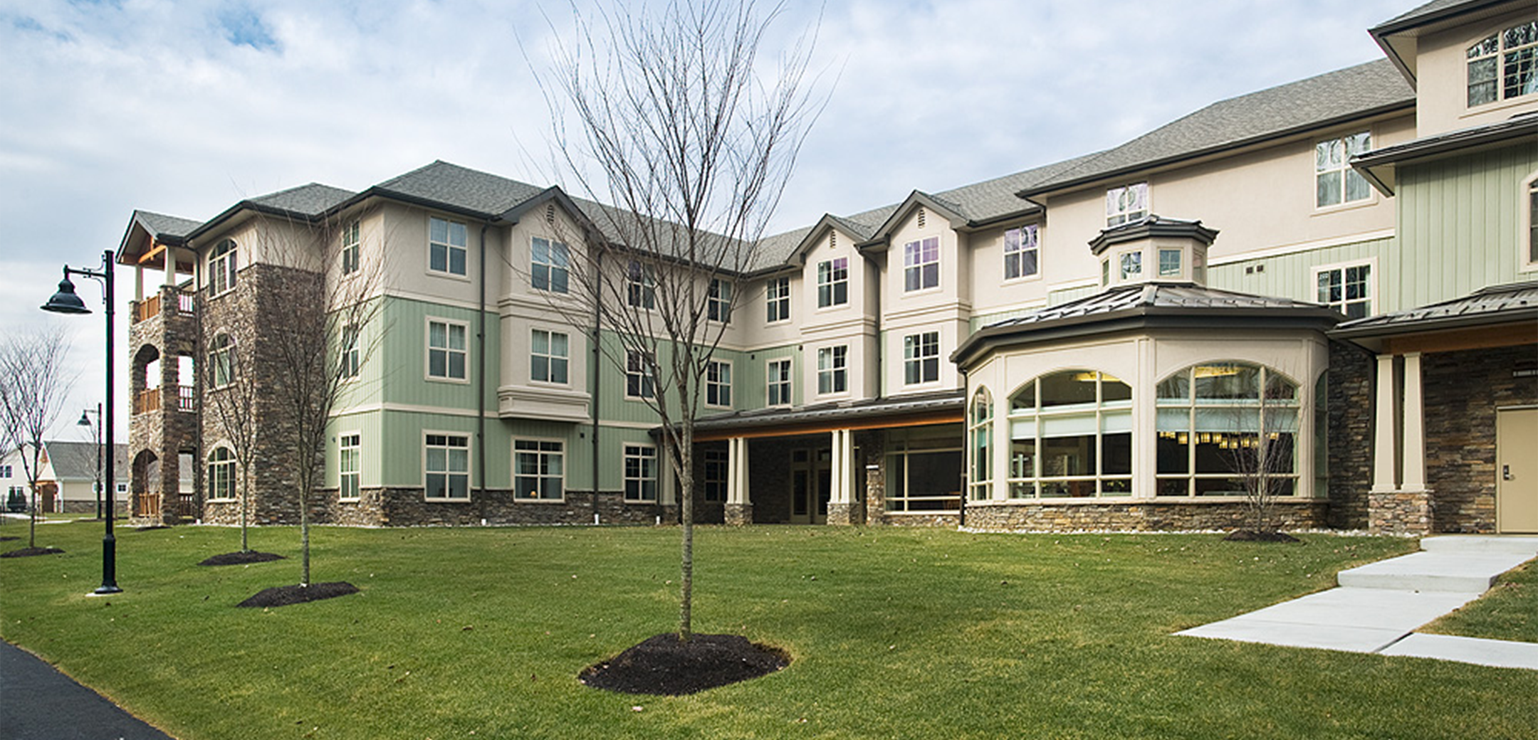 An angled exterior view of the Vantage Point back side showcasing stone brick, mint and white colored building, and large green grass field.