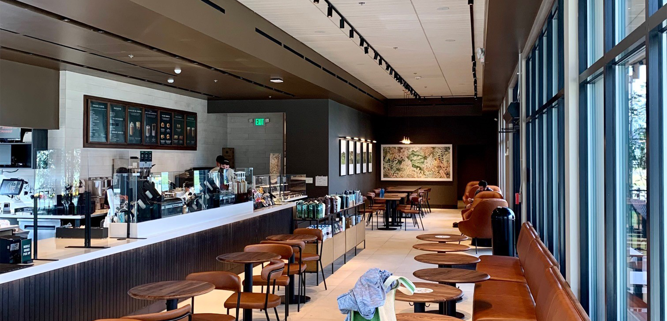 The interior view of the Starbucks seating area and bar counter, showcasing the leather seats attached to the glass window and wooden tables along the wall.