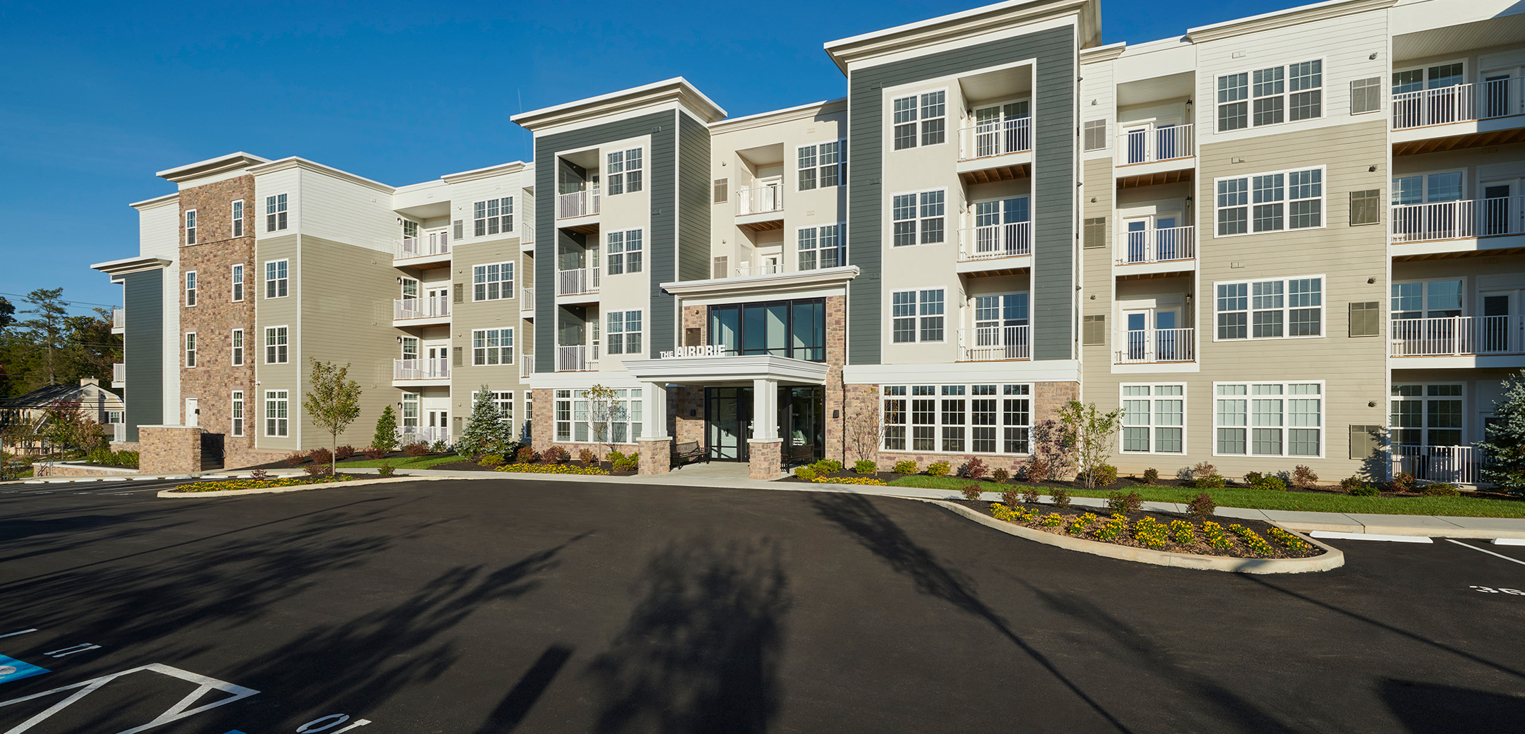 An exterior view of one of the Station Square apartment buildings showcasing the front door entrance with an overhang and a wheelchair accessible parking lot.