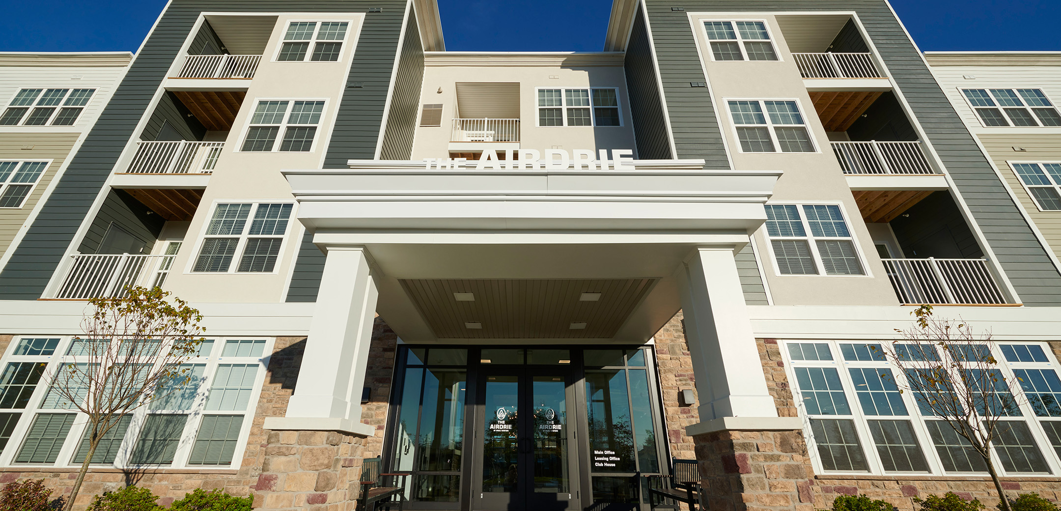 A close up view of the Station Square apartments front entrance with an overhang that has a ``the AIRDRIE`` signage on it.