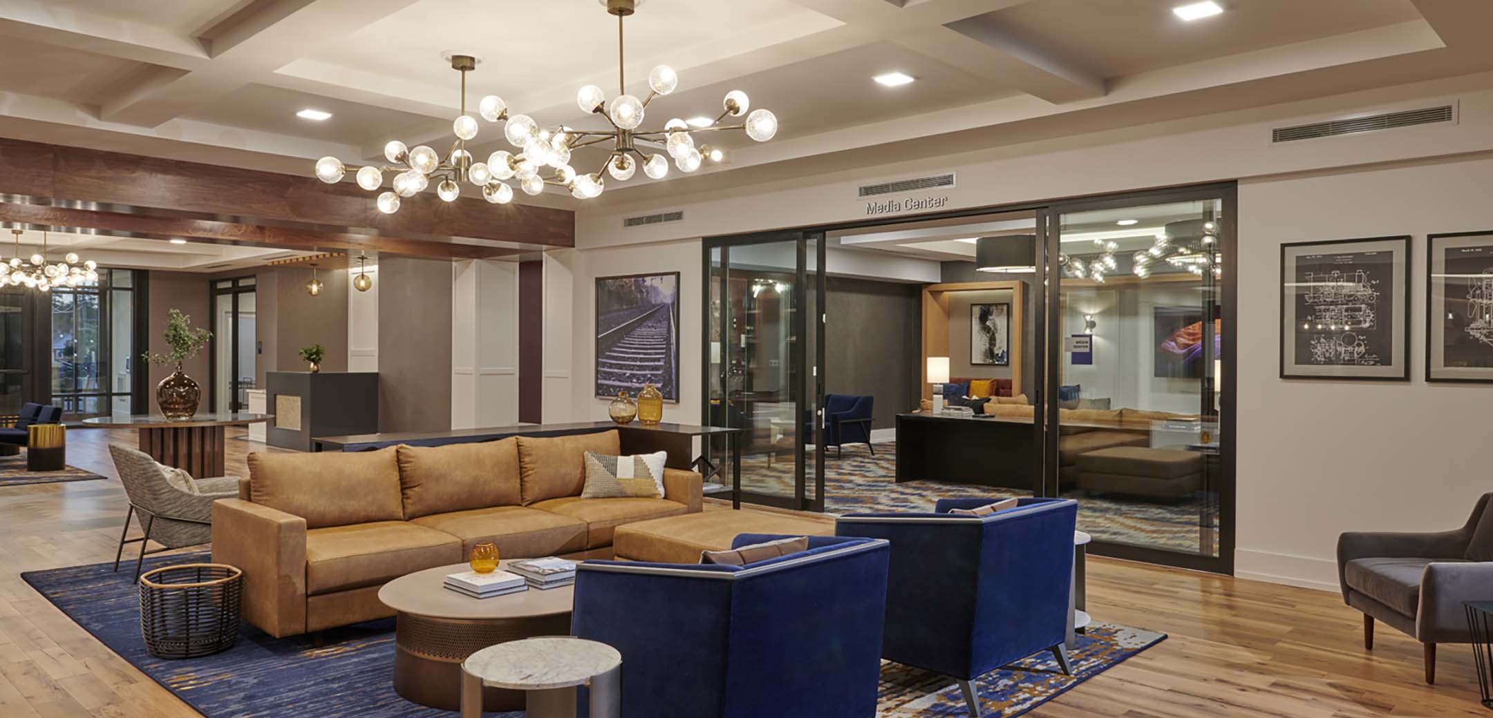 An interior view of the Airdrie building lobby, with couches and chairs in the reception sitting area and a media center room in the background.