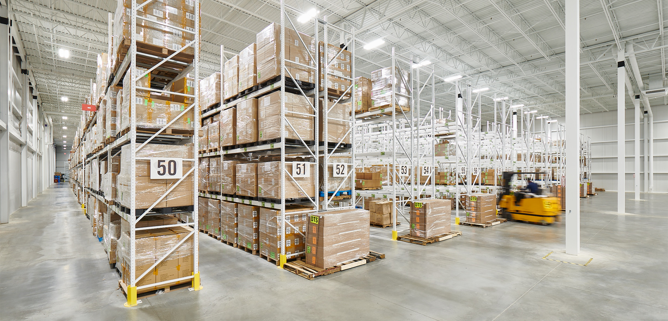 An interior view of the Streamlight warehouse, showcasing the well lit, white, tall ceiling, rows of storage shelves.