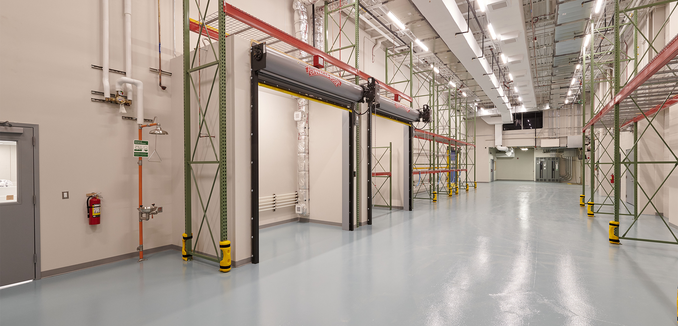 An angled interior view of the Veltek building warehouse with large shutter hangar doors and a high ceiling with exhaust vents routing along it.