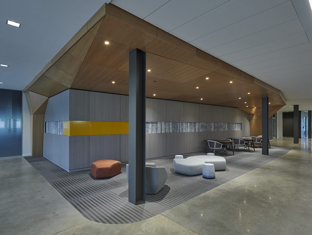An interior view of the office lobby with a seating area and a wood paneled accent wall.