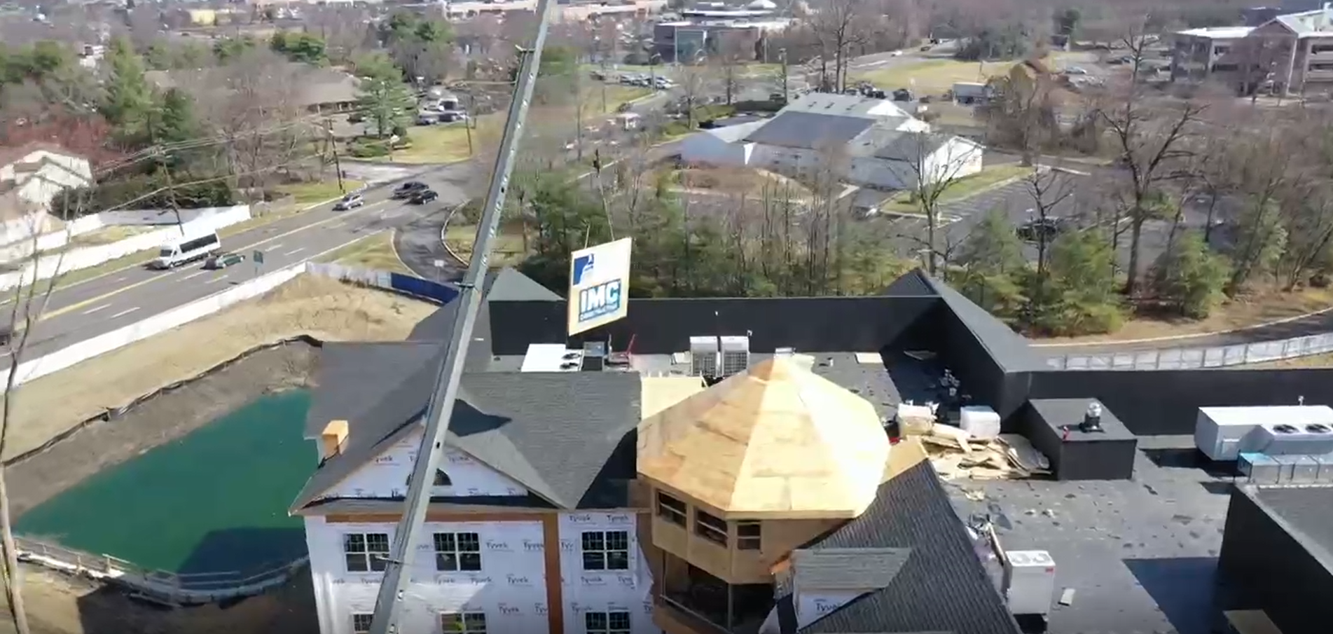 an aerial view of a crane carrying a topping out piece of wood for Arbor Terrace Marlton