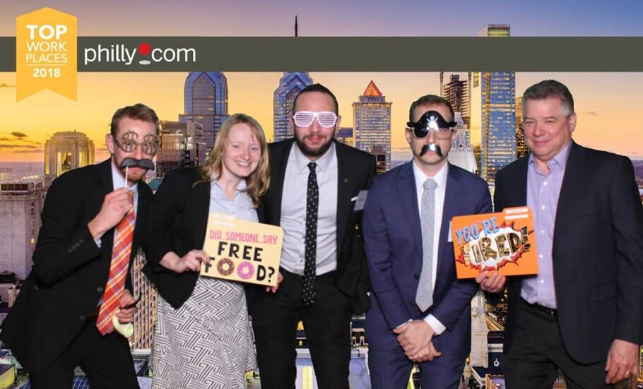 A group photo of five members of IMC Construction celebrating with signs and gag props.