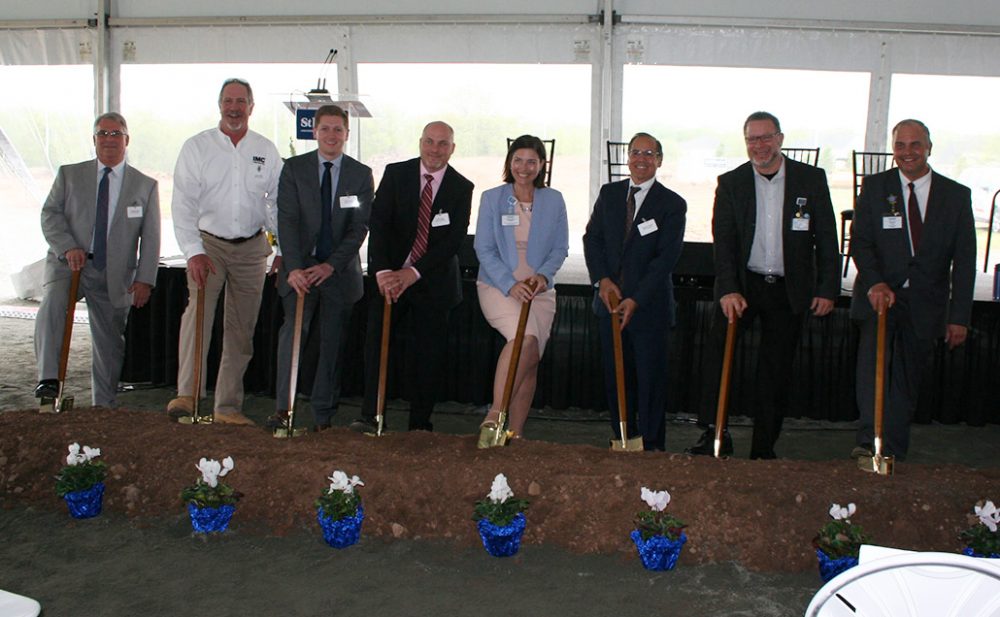 A picture of the ground breaking ceremony with eight individuals holding shovels and celebrating the new hospital.