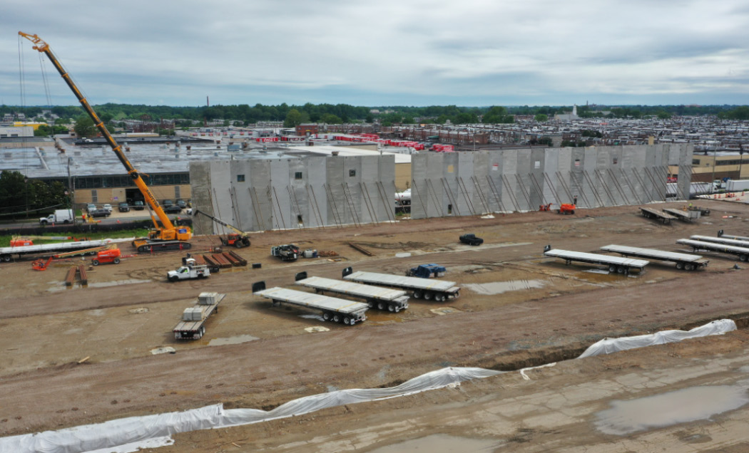 Tilt-up panels being installed at Crown 95 Logistics Center with large flatbeds in foreground