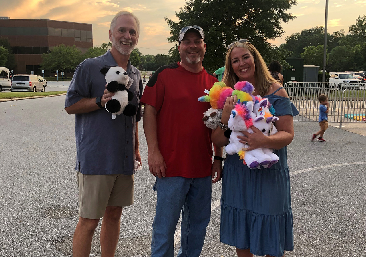 3 IMC employees posing for a photo with stuff animals in their hands