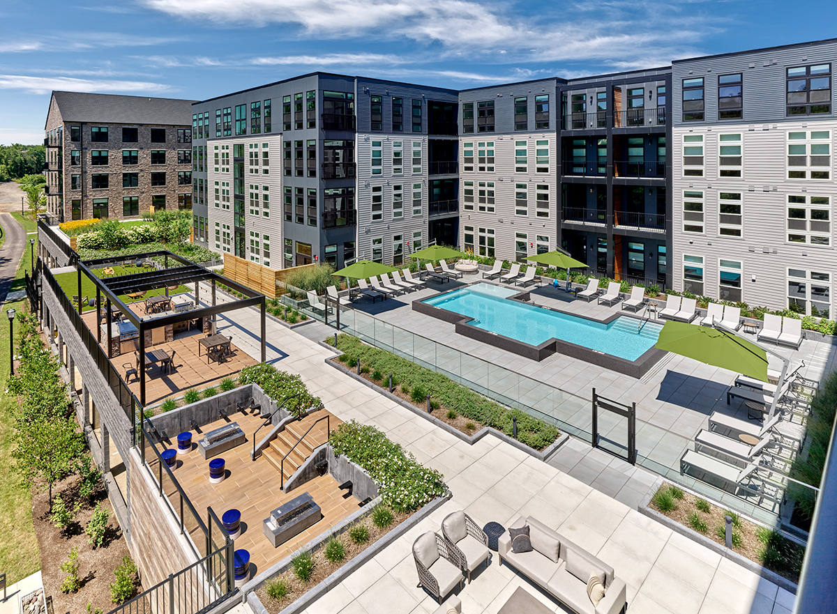 An aerial view of Matson Mill Apartment's outdoor terrace featuring a resort-style pool, sunken lounge, outdoor seating, and sun deck.