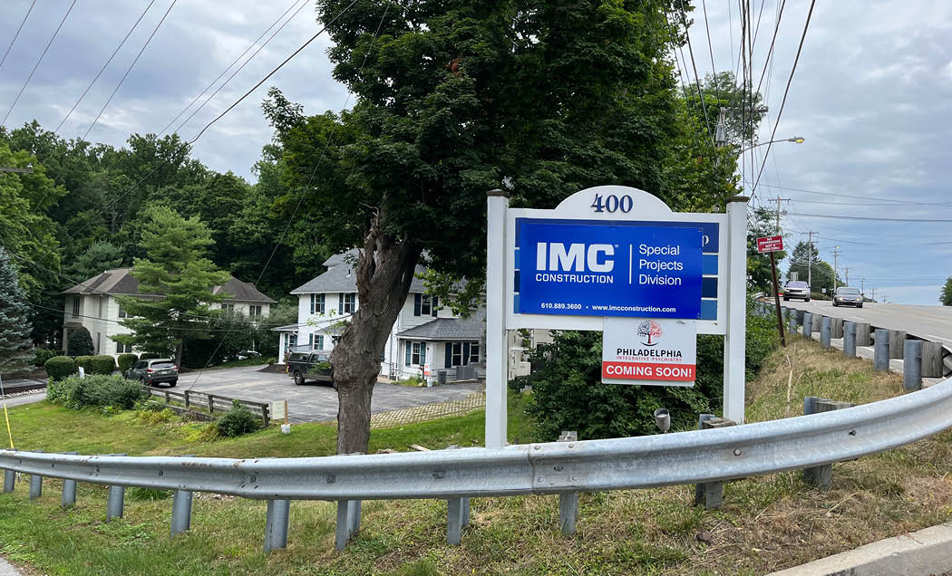 A blue sign that says ``IMC Construction Special Projects Division`` on the corner of the Philadelphia Integrative Psychiatry Office