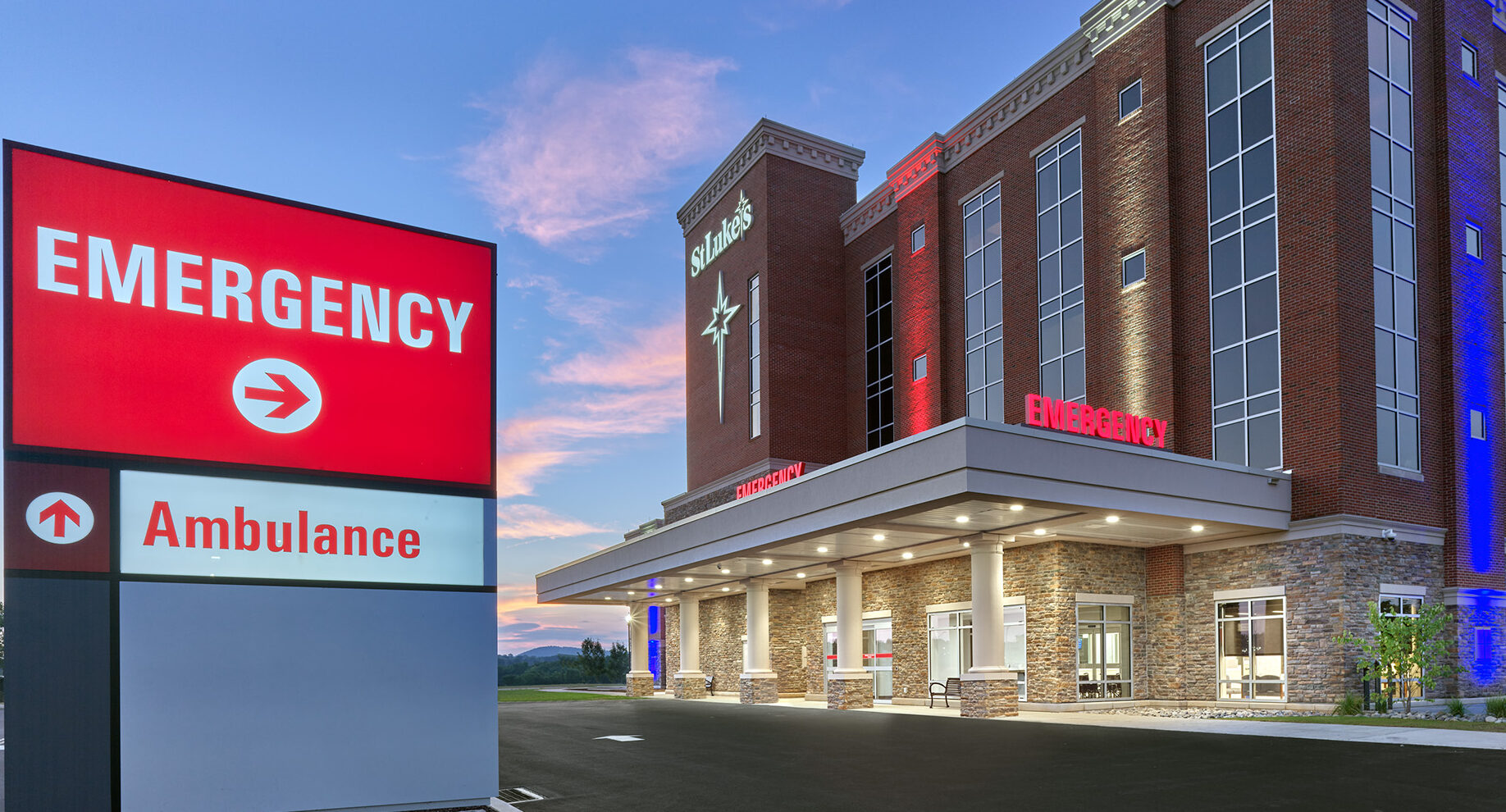 The side view of St. Luke`s Anderson Campus exterior with the emergency department sign in front and the brick building light up in the dark